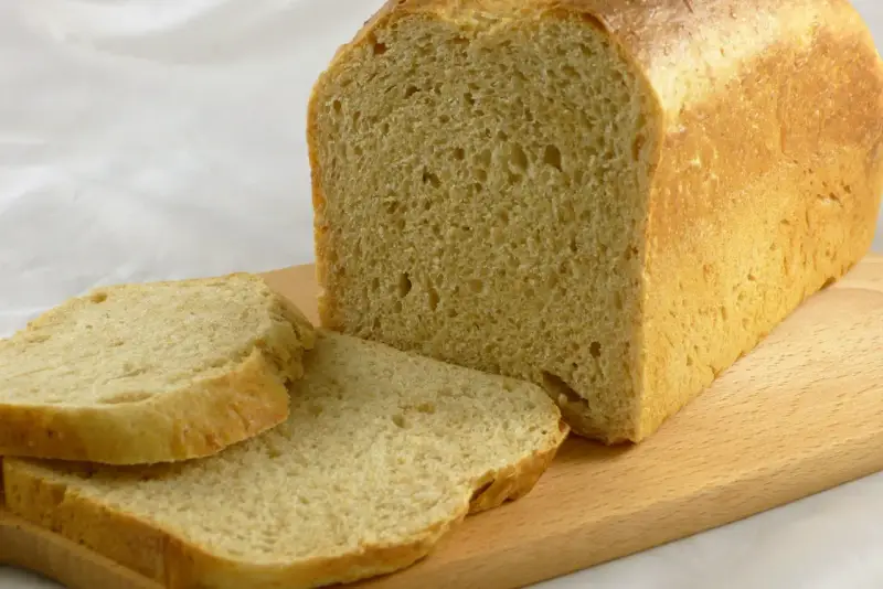 Frisch gebackenes Brot, das wie aus Buchweizen und anderen Getreidesorten gemacht aussieht, liegt auf einem Holzbrett.