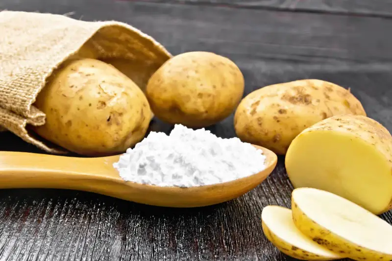Kartoffeln und ein Löffel voller Kartoffelstärke, eine vielseitige kartoffelmehl alternative für Küche und Haushalt.